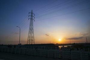 Silhouette of the high voltage power line at sunset in Narayanganj, Bangladesh photo