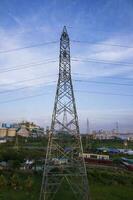 High voltage electricity pylon with cityscape and blue sky background. photo