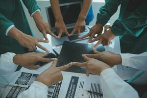 Doctors and nurses in a medical team stacking hands photo