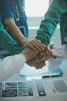 Doctors and nurses in a medical team stacking hands photo