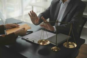 Business and lawyers discussing contract papers with brass scale on desk in office. Law, legal services, advice, justice and law concept picture with film grain effect photo