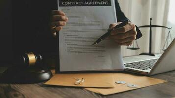 Business and lawyers discussing contract papers with brass scale on desk in office. Law, legal services, advice, justice and law concept picture with film grain effect photo