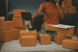 Startup small business entrepreneur or freelance Asian woman using a laptop with box, Young success Asian woman with her hand lift up, online marketing packaging box and delivery, SME concept. photo