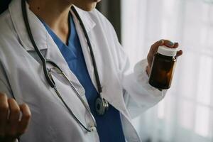 Young doctor with diary sitting at desk in medical clinic photo