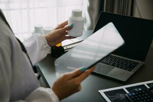 Doctor working with laptop computer and writing on paperwork. Hospital background. photo