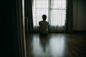 Alone man silhouette staring at the window closed with curtains in bedroom. Man stands at window alone photo