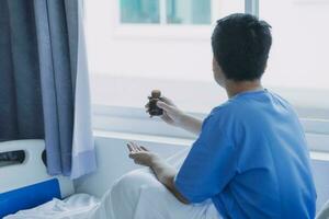 patient sat on the bed and looked out the window in the hospital alone and had stress, boredom, loneliness, anxiety.  Health care and medical photo