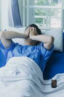 young injured man in hospital room sitting alone in pain looking negative and worried for his bad health condition sitting on chair suffering depression on a sad lonely medical background photo