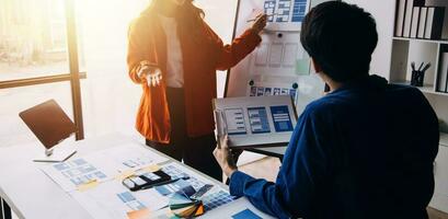 Close up ux developer and ui designer brainstorming about mobile app interface wireframe design on table with customer breif and color code at modern office.Creative digital development agency photo