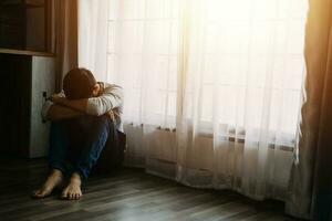 Alone man silhouette staring at the window closed with curtains in bedroom. Man stands at window alone photo