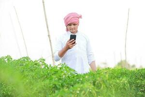 Young indian farmer showing Smart phone , Farmer talking on phone in farm, happy indian farmer photo