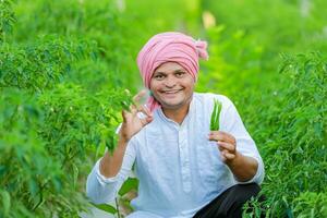 Indian Happy farmer holding green chilli , green chilli farming, young farmer photo