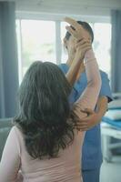 young asian physical therapist working with senior woman on walking with a walker photo