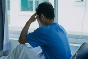 patient sat on the bed and looked out the window in the hospital alone and had stress, boredom, loneliness, anxiety photo