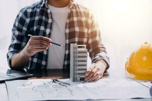 reunión de trabajo en equipo de ingenieros, trabajo de dibujo en la reunión de planos para el trabajo del proyecto con un socio en la construcción de modelos y herramientas de ingeniería en el concepto de sitio de trabajo, construcción y estructura. foto