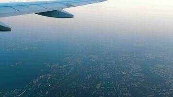 View of the wing of the aircraft and the clouds from the porthole. City view video