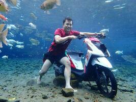 Klaten, Umbul ponggok, Indonesia, July 22, 2022,  a man taking a photo under clear water