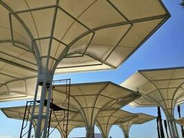 edificio estructura, un membrana paraguas con un minimalista diseño a sala apagado caliente clima durante el día foto
