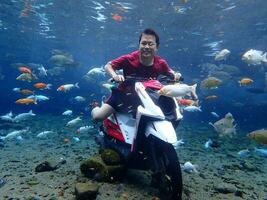 Klaten, Umbul ponggok, Indonesia, July 22, 2022,  a man taking a photo under clear water