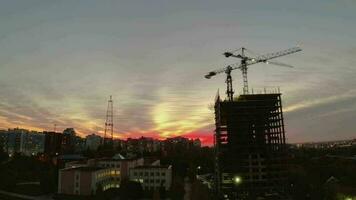 rojo puesta de sol en el ciudad. construcción de un edificio en contra el fondo de un brillante puesta de sol video
