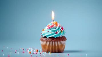 Birthday cupcake with a candle on light blue background with balloons. photo