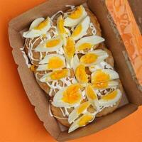 Delicious homemade bread with boiled egg in cardboard box on orange background photo