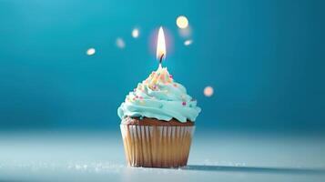 Birthday cupcake with a candle on light blue background with balloons. photo