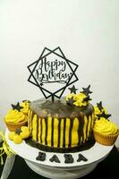 Birthday cake decorated with black and yellow buttercream frosting. photo