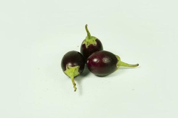 Lot of lot of vibrant green scarlet eggplant vegetable on top of each other  against a black background. Graphic minimalist image of food. Stock Photo