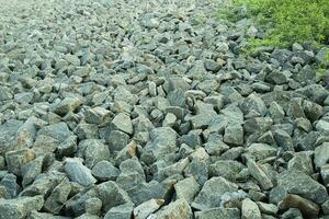 Pile of stones on the beach with green trees in the background photo