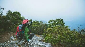 Asian woman travel nature. Travel relax. Sit and watch nature landscapes on the cliff. Vacation on the mountains. photo