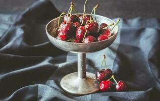 Fresh cherries in vintage silver vase photo