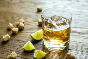 Glass of rum on the wooden background photo