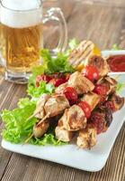 Grilled chicken skewers with mug of beer photo