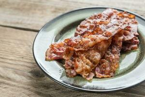 Stack of fried bacon strips on the plate photo