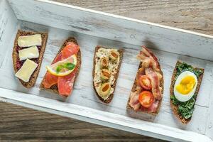 Bruschetta with different toppings on the wooden tray photo