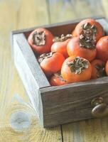 Wooden box of fresh persimmons photo