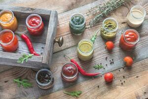 Assortment of sauces in the glass jars with ingredients photo