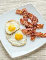 Portion of fried eggs with bacon photo