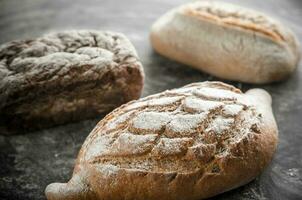 Whole grain breads on the dark wooden background photo