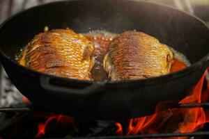 el pescado es frito en un pan en petróleo en un fuego. Cocinando pez. foto