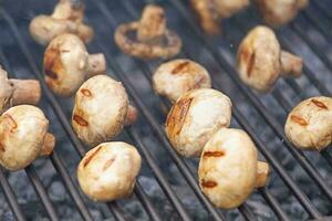 Mushrooms are cooked on the grill. Delicious mushrooms on the fire. photo