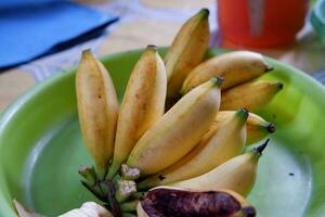 amarillo y ligeramente podrido bananas en un verde bandeja foto