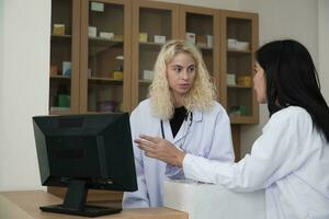 wo profesional médico personal, asiático hembra doctor, y blanco farmacéutico discutido tratamiento medicina recetas a mostrador de el farmacia Departamento en hospital clínica. foto