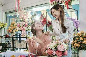 retrato de dos alegre joven hermosa hembra florista socios equipo sonriente y mirando juntos floración ramo de flores contento trabajo en vistoso flor tienda Tienda con Fresco flora, SME negocio emprendedor. foto