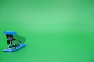 stapler isolated green background. Front view of the mini stapler. photo