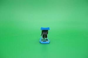 stapler isolated green background. Front view of the mini stapler. photo
