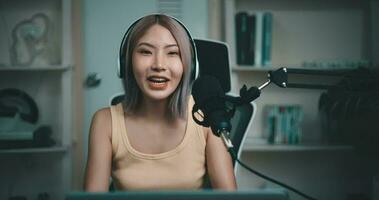 Aufnahmen von jung asiatisch Frau Influencer tragen Kopfhörer reden in ein Mikrofon während Aufzeichnung ein Radio Show im ein Leben Zimmer Zuhause Studio. Inhalt Schöpfer und Influencer Marketing Konzepte. video