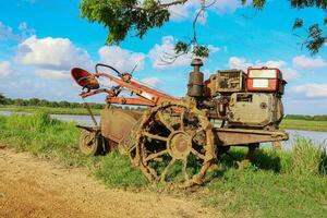 antiguo oxidado tractor en el campo con azul cielo antecedentes. foto