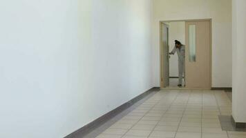 Medical sister in professional uniform with two funny children in the corridor of hospital. video